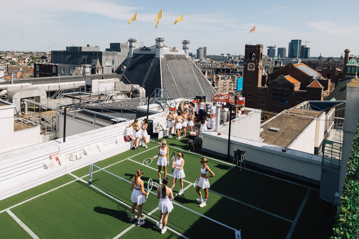 Kunstrasenplatz mit weißen Linien und der Skyline von Amsterdam im Hintergrund